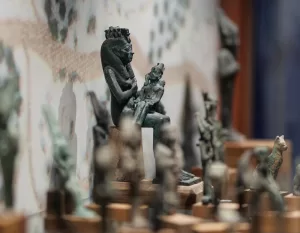 MAEC Cortona collezione egizia. Scultura in bronzo di Iside seduta con Horus sulle ginocchia, in atto di allattarlo, su base trapezoidale.